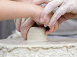 Artisan learning a child to make potter from white clay.