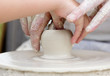 Artisan learning a child to make potter from white clay.