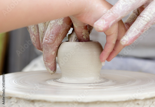 Photo: Artisan learning a child to make potter from white clay. Artisan learning a child to make potter from white clay.