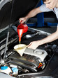 Motor mechanic topping up oil of a car in a garage
