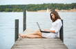 Foto: attraktive junge Frau, die am Laptop am Wasser arbeitet attraktive junge Frau, die am Laptop am Wasser arbeitet