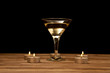 glass of martini with candles on a wooden table