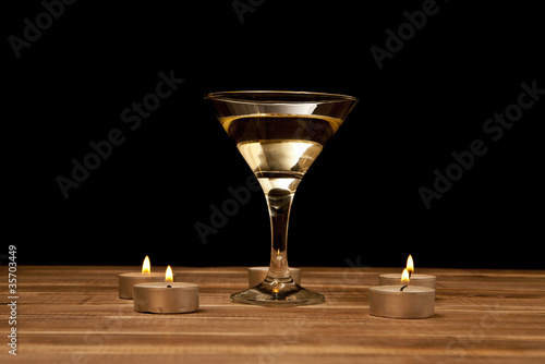 Photo: glass of martini with candles on a wooden table glass of martini with candles on a wooden table