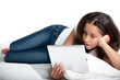 Foto: Teenage girl holding tablet computer lying down. Teenage girl holding tablet computer lying down.