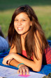 Pretty young female college student studying on a campus field
