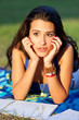 Pretty young female college student studying on a campus field