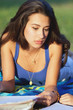 Pretty young female college student studying on a campus field