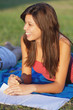 Pretty young female college student studying on a campus field