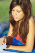 Pretty young female college student studying on a campus field