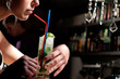 A young blond girl drinking coctail mohito with a straw in a caf