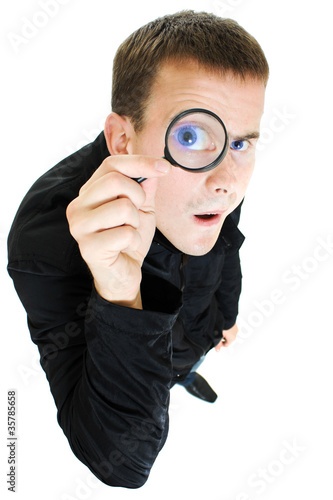 Photo: Funny man looking through a magnifying glass. Funny man looking through a magnifying glass.