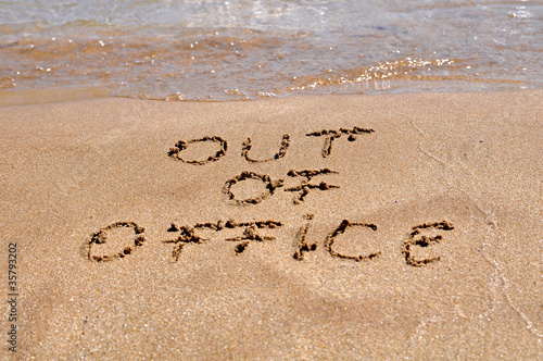 Photo: Out of office text written on the beach sand Out of office text written on the beach sand