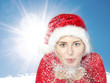 Nice woman with Santa Claus hat blowing snow in winter