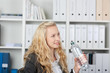 frau im büro mit wasserflasche