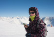 Skier in the mountains with a mobile phone in his hand