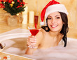 Woman in santa hat relax in bath.