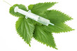 Syringe with medicine on green leaves isolated on white