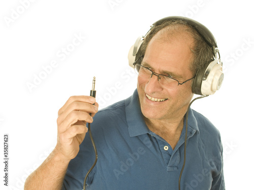 Photo: senior man wearing music head phones looking at plug senior man wearing music head phones looking at plug