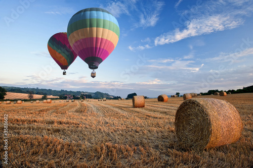 Foto: Hot air balloons over hay bales sunset landscape Hot air balloons over hay bales sunset landscape