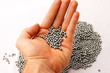 BB pellets in hand over pile of silver pellets