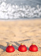 Three red Christmas balls on sea coast Three red Christmas balls on sea coast