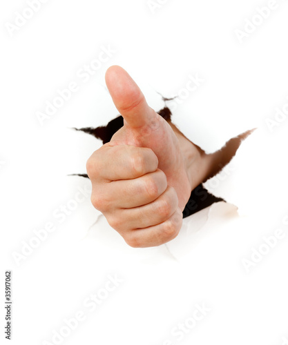 Photo: Hand with thumb up through a hole in paper Hand with thumb up through a hole in paper