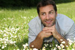 man lying in daisy field man lying in daisy field