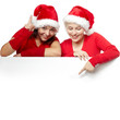 Foto: Pretty girls with santa hat showing something on copyspace Pretty girls with santa hat showing something on copyspace