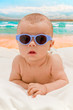 Funny baby in sunglasses on the beach