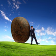 Businessman rolling a giant stone