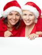 Two girls with santa hat smiling and showing copyspace