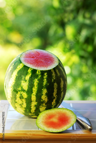 Photo: Watermelon and knife on table. Watermelon and knife on table.