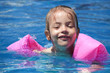 Joyful little girl swimming in the pool.