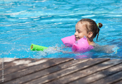 Photo: Joyful little girl swimming in the pool. Joyful little girl swimming in the pool.