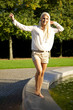 Cute woman balancing on fountain wall