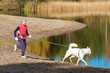 The sports woman with a dog run along coast of the rivers