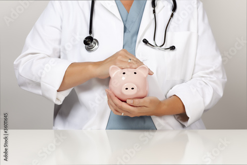 Photo: Doctor with Stethoscope Holding Piggy Bank Abstract Doctor with Stethoscope Holding Piggy Bank Abstract