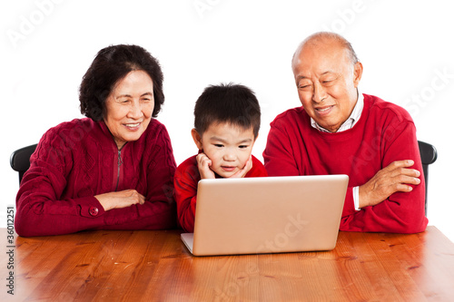 Photo: Senior Asian grandparents using computer with their grandson Senior Asian grandparents using computer with their grandson