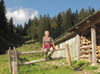 Frau bei Wanderung sitzt auf Zaun