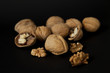Cracked and whole walnuts in black background