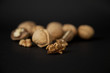 Cracked and whole walnuts in black background
