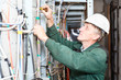 Photo: Mature electrician working in hard hat with cables and wires Mature electrician working in hard hat with cables and wires