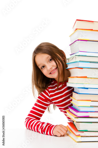 Foto: Girl peeking behind pile of books on white background Girl peeking behind pile of books on white background