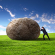 Businessman rolling a giant stone