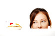 Girl hiding behind the desk and looking at the cake.