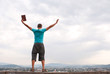 Young man staying with raised hands against blue sky
