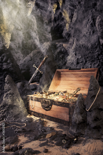 Photo: open treasure chest with bright gold in a cave open treasure chest with bright gold in a cave