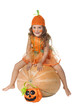 Girl dressed like Cinderellai sits on a pumpkin.