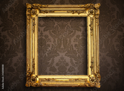Photo: Empty golden painting frame on vintage wallpaper Empty golden painting frame on vintage wallpaper