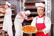 Male baker holding a pizza in bakery Male baker holding a pizza in bakery
